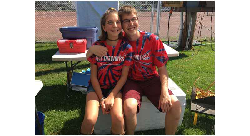 two smiling people sitting at the fireworks celebration